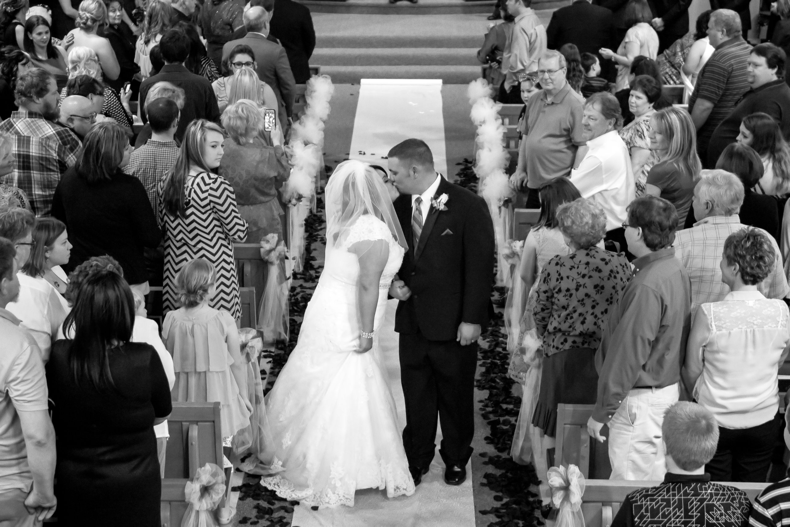 bride and groom kissing in the aisle in black and white