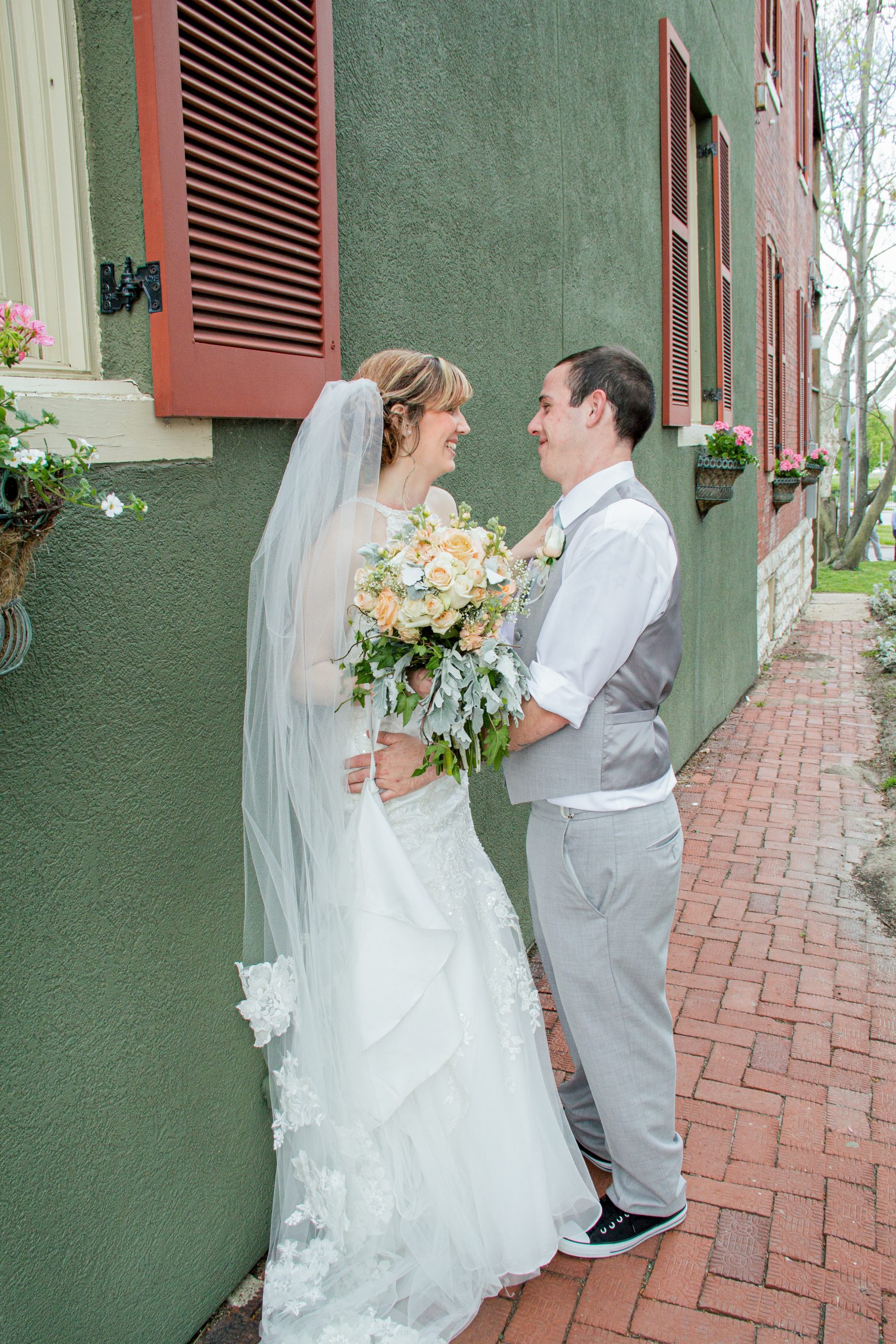 bride and groom leaning on wall smiling at each other