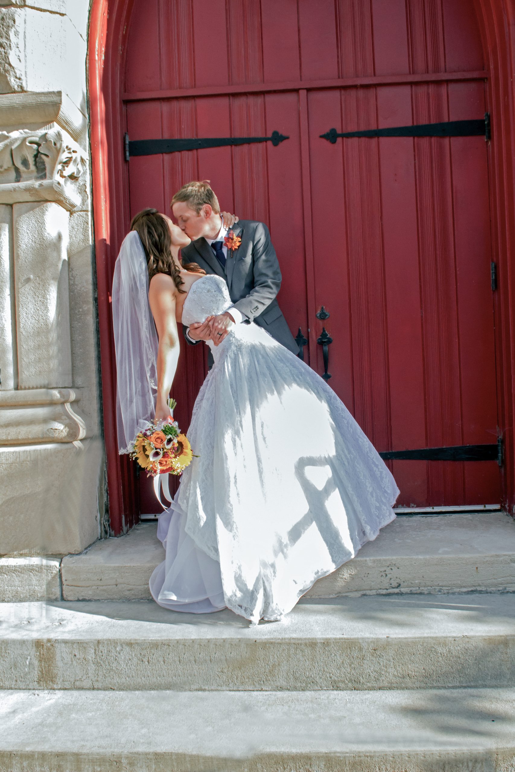 groom dipping bride and kissing at doors to the church