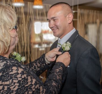 mother attaching boutonniere to groom