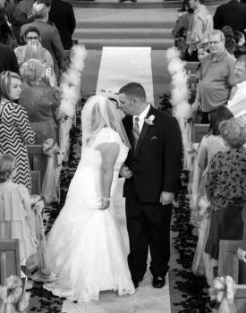 bride and groom kissing in the aisle in black and white