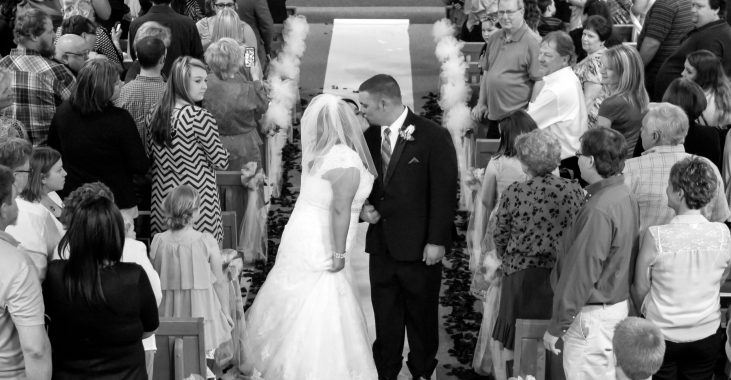 bride and groom kissing in the aisle in black and white