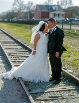 bride and groom kissing on train tracks