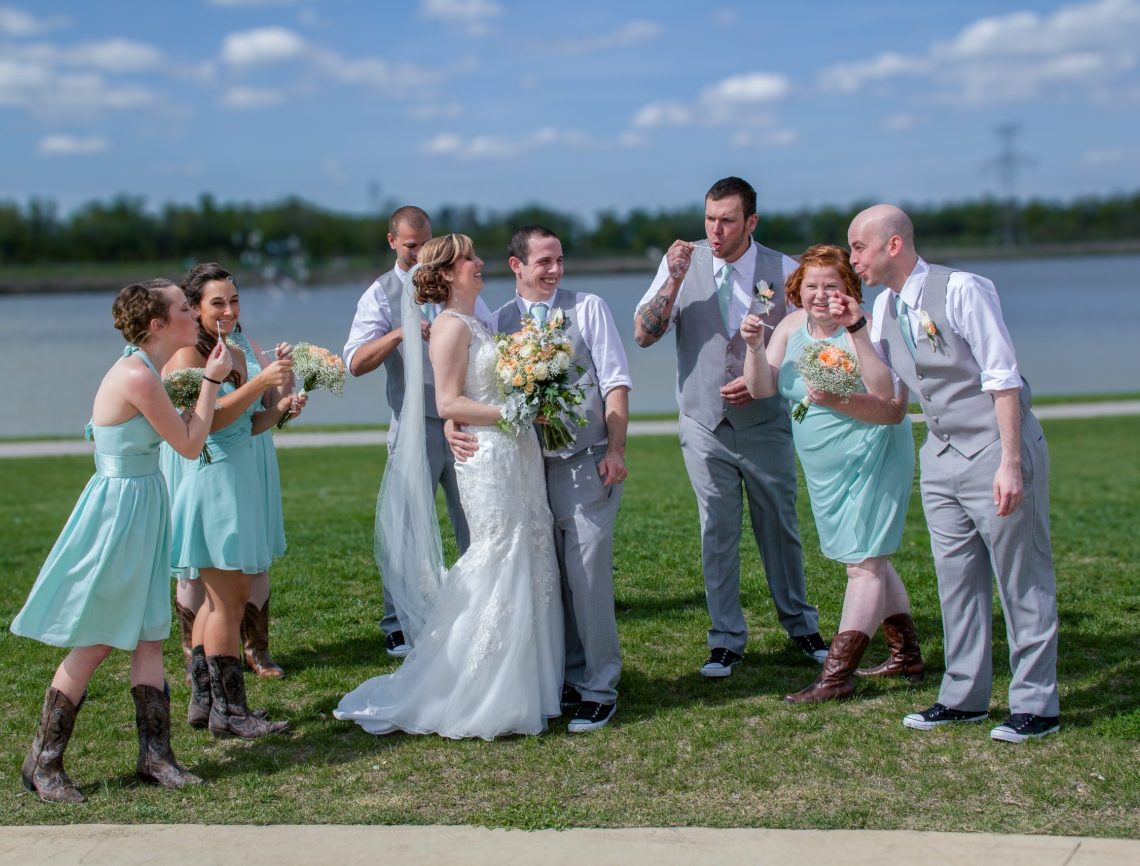 wedding party blowing bubbles at bride and groom
