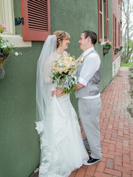 bride and groom leaning on wall smiling at each other