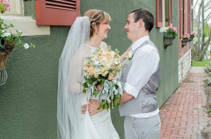 bride and groom leaning on wall smiling at each other