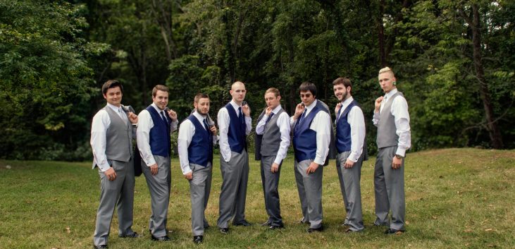 Groom and groomsmen outside with jackets over shoulder