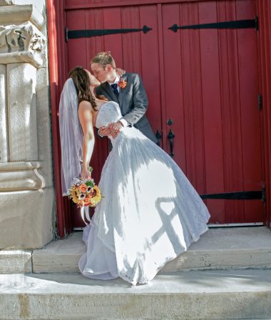 groom dipping bride and kissing at doors to the church
